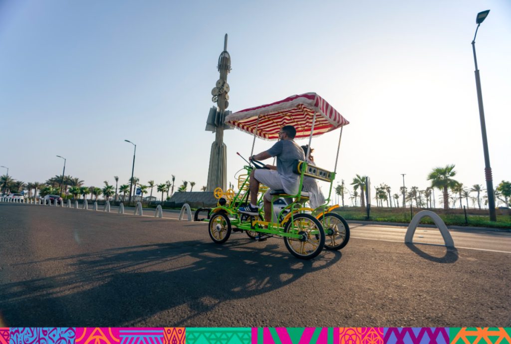 A man and a little girl riding a surry bicycle on the street of the Jeddah Corniche,  Djedda