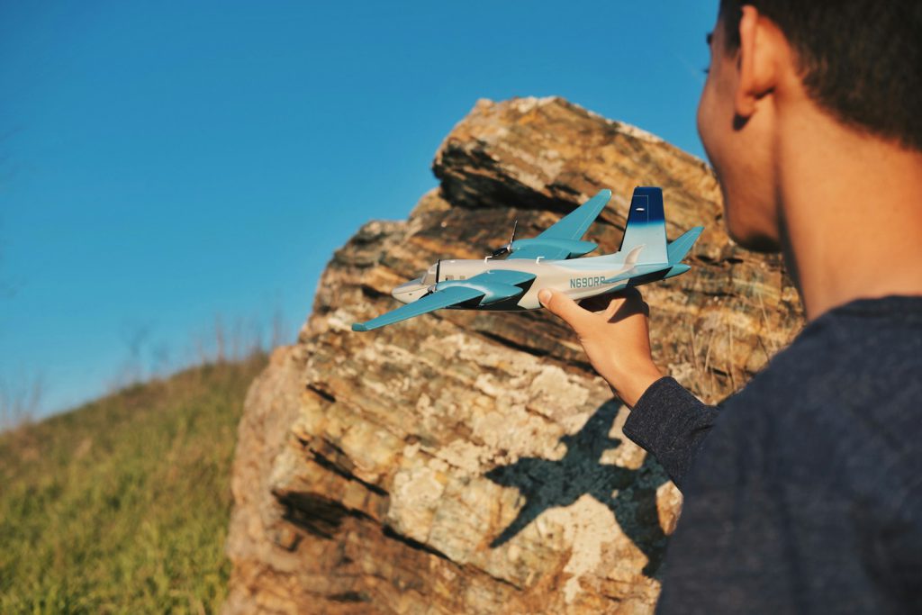 person holding blue airliner beside rock vliegen met peuters kid kind vliegtuig