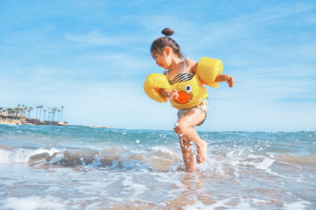 girl playing beside body of water during daytime kind meisje in zee met zwemvleugels zwembandjes